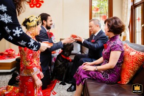 Een speelse hond voegt een vleugje kattenkwaad toe aan de traditionele Chinese theeceremonie, met de zittende ouders in Haining, China.